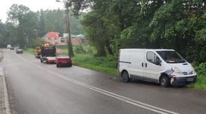 biały bus z rozbitym przodem w tle czerwona mazda i holownik samochód pomocy drogowej