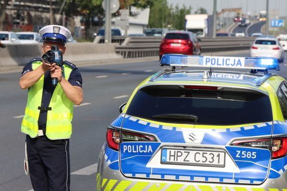 policjant z miernikiem prędkości na ulicy miasta obok radiowozu