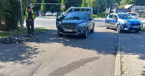 skrzyżowanie w Nałęczowie na ulicy leży rower pochyla się nad nim policjant obok stoi suv Ford za nim radiowóz w tle jadą samochody