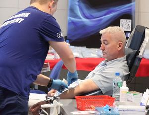 policjant po cywilnemu oddający krew nad nim pielęgniarz podpinający wężyk do igły w ręce