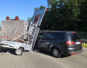czarny ford galaxy stojący przodem pod uszkodzonymi znakami ostrzegawczymi na przyczepce samochodu słuzby drogowej