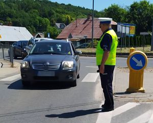 policjant na drodze patrzący na podjeżdżającą do niego osobową toyotę
