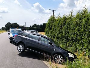 czarna toyota w rowie za nią bus policyjny