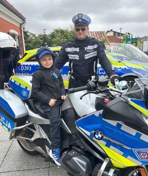 policjant ruchu drogowego z dzieckiem pozującym na policyjnym motocyklu