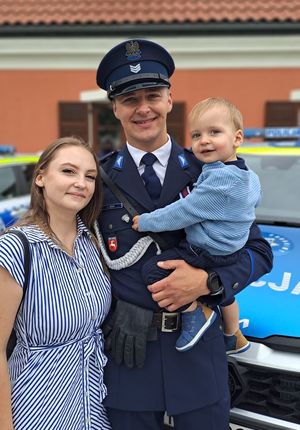 policjant w mundurze z żoną i dzieckiem na rękach