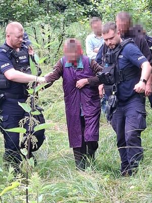 policjanci prowadzący seniorkę