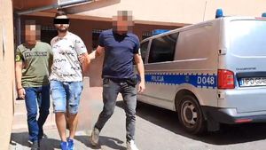 Policjanci prowadzą zatrzymanego mężczyznę.