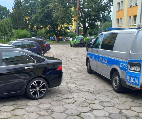 policyjny bus na parkingu między samochodami