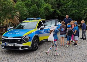 dzielnicowy prezentujący grupie dzieci radiowóz