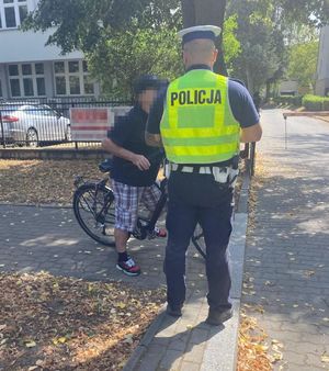 policjant stojący obok mężczyzny na rowerze