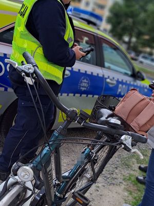 rower obok niego policjantka w tle radiowóz