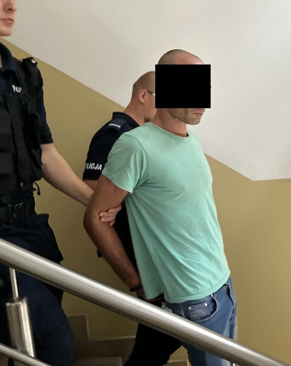 policjanci prowadzący zatrzymanego mężczyznę