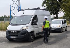 dwa samochody na drodze obok policjant ruchu drogowego