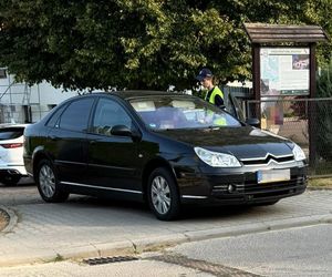 czarny citroen wyjeżdżający z bramy obok niego policjantka