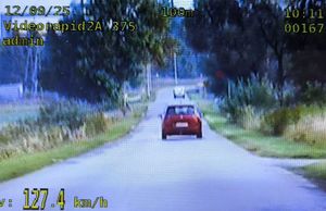 zrzut ekranu na nim droga i czerwony samochód jadący z prędkością 127 km na godzinę