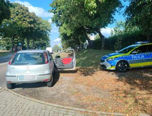 szary opel corsa stojący przy drodze obok radiowóz