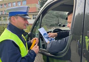 policjant przekazujący ulotki kierowcy