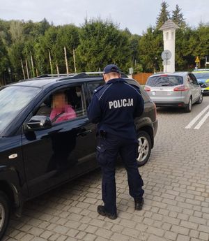 policjant kontrolujący kierującą granatowym samochodem