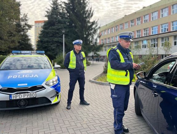 policjanci przed szkołą obok radiowóz