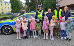 dzieci z przedszkola pozujące z policjantami obok radiowozów