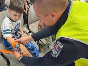 policjant zakładający dziecku opaskę odblaskową na przedramię