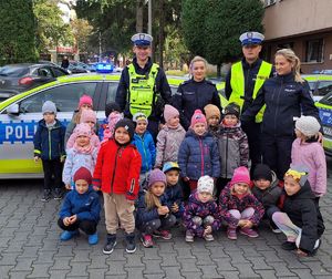 policjantki i policjanci pozujący przed komendą z dziećmi z przedszkola nr 15