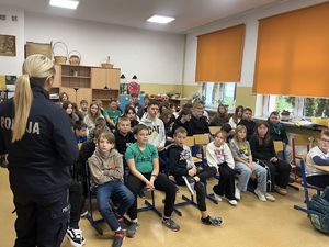uczniowie w klasie przed nimi policjantka prowadząca prelekcję