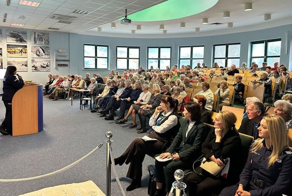 Policjantka przemawiająca do ludzi na sali wykładowej