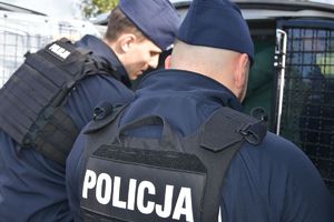 policjanci obok zakratowanej szyby radiowozu