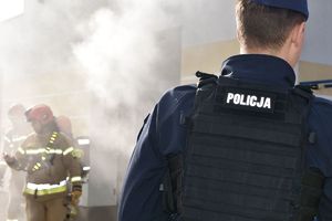 strażacy w dymie na pierwszym planie policjant