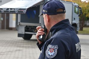 policjant rozmawiający przez radiostację w tle samochód kontrterrorystów