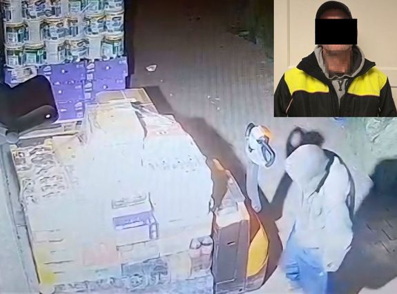 zrzut ekranu z kamery na nim zakapturzona postać obok towaru na palecie w rogu zdjęcia sylwetka mężczyzny z zasłoniętą twarzą