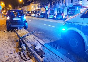 czarny smart stojący częściowo na chodniku obok radiowóz