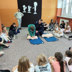 policjant uczący dzieci na fantomach pierwszej pomocy przedmedycznej