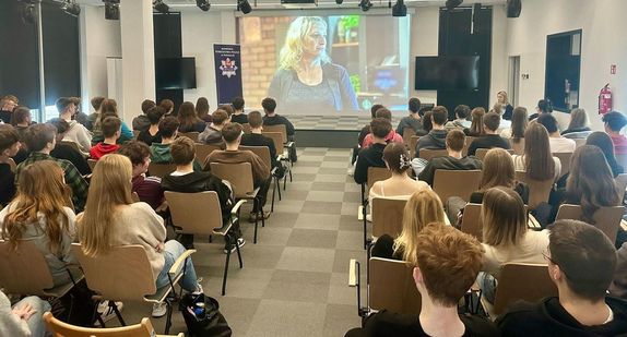 ekran na nim wyświetlona prezentacja i cała sala młodzieży