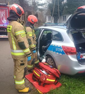 strażacy podający tlen mężczyźnie siedzącemu w radiowozie