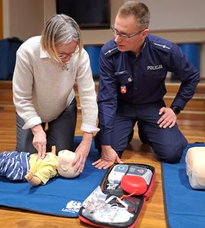 policjant uczący seniorkę udzielania pierwszej pomocy niemowlęciu