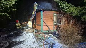 strażacy gaszący drewniany dom