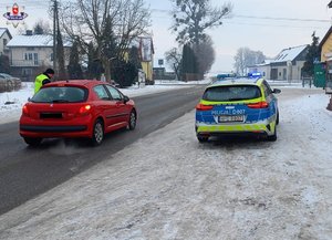radiowóz obok niego czerwony samochód osobowy przy nim policjant badający kierowcę na trzeźwość
