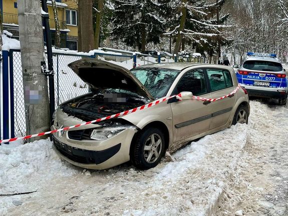 szary samochód oparty o słup w tle radiowóz