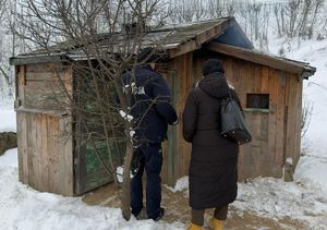 dzielnicowy i pracownica ops obok małego drewnianego budynku