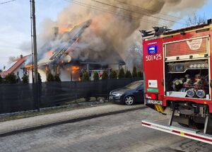 płonący dom obok samochód straży pożarnej i osobowy opel