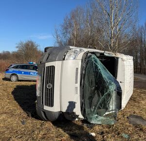 biały bus leżący na boku w tle radiowóz
