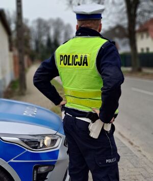 policjant ruchu drogowego obok radiowozu przy drodze