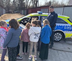dzielnicowy z dziećmi obok radiowozu
