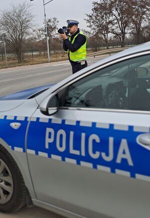policjant z miernikiem prędkości przy drodze