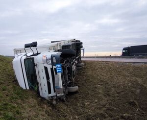 biała ciężarówka leżąca na boku w rowie