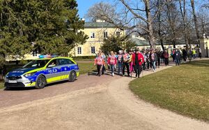 radiowóz i osoby idące za nim drogą