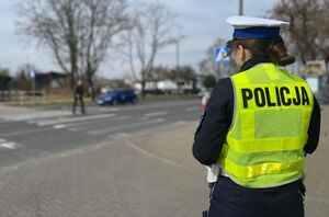 policjantka obserwująca przejście dla pieszych po którym kobieta prowadzi rower