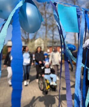 niebieska dekoracja z bibuły i balonów w tle osoba na wózku inwalidzkim